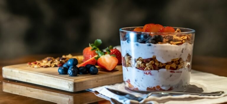 Layered berry and cream parfait in a clear glass with fresh strawberries